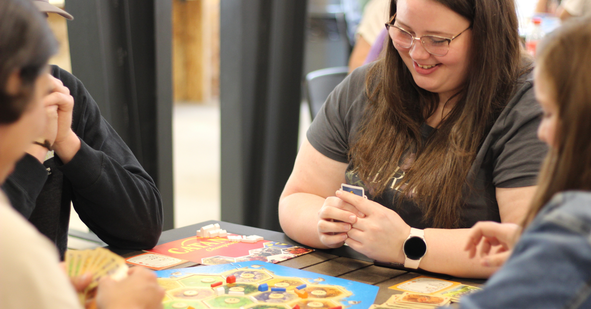 A woman laughing while playing Catan with a local board game group in Saskatoon.