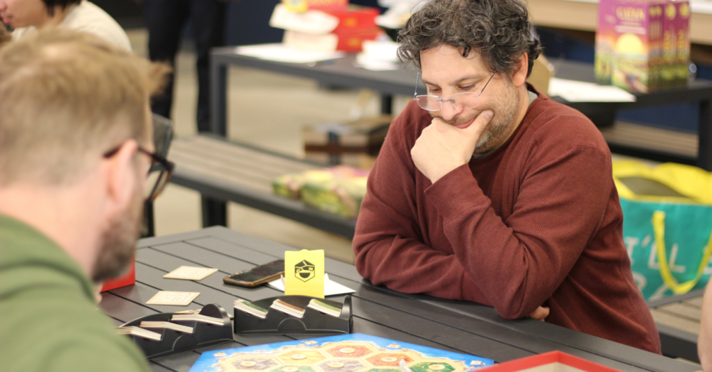 A man thoughtfully planning his next move during a casual board game night in Saskatoon.